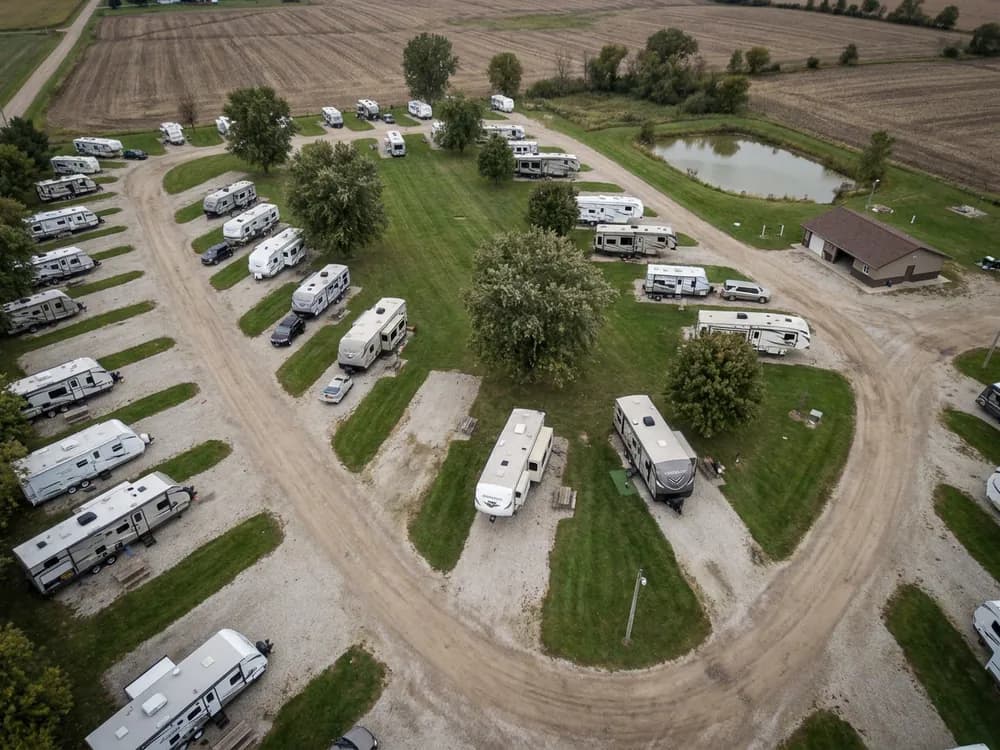 Drone view of an RV park with rows of travel trailers on gravel pads along curving roads