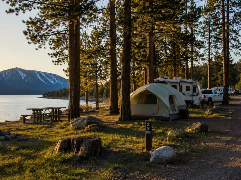 Tent and RV at a lakeside forest campground at golden hour