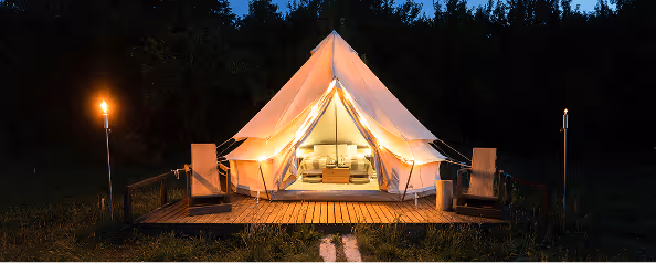 Luxury glamping tent illuminated at night with warm interior lighting
